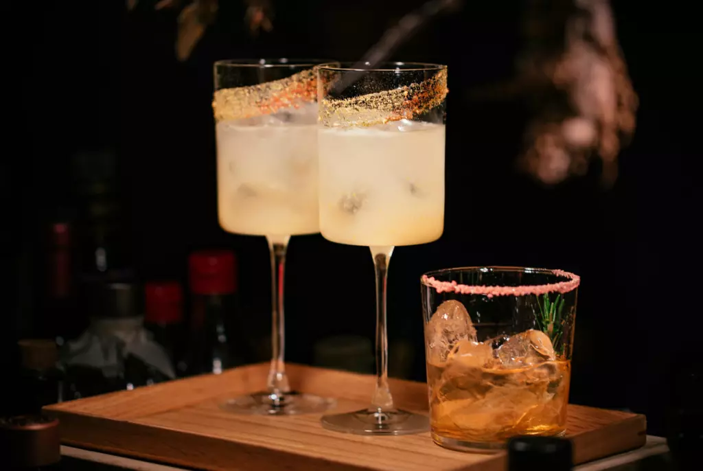 Three glass with beverages and garnishes.