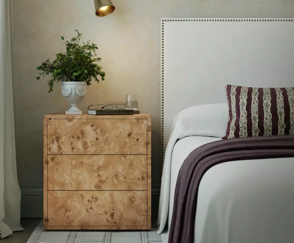 A crop of a bedroom with section of bed and bedside table with lamp.