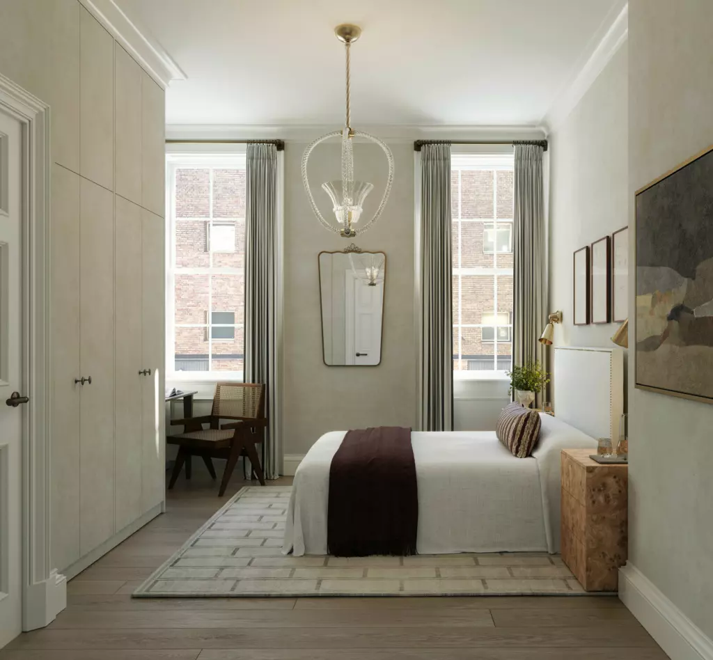 Bedroom with large ceiling light fitting, bed, fitted wardrobes and double windows.